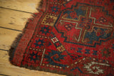 Vintage Beshir rug's worn red pile, edge, and navy geometric patterns.