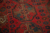 Cherry red, navy blue, ivory geometric gul motif, visible knot heads.