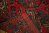 Worn edge of a vintage Beshir rug, highlighting cherry red field, navy gul motifs, and foundation wear.