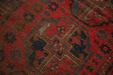 Close-up of vintage Beshir rug's cherry red field, navy blue gul motif, and worn knot heads.