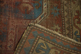 Antique Kazak rug detail: worn madder red and blue pile, hand-knotted foundation, running T border, fringe.