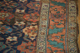 Antique Kurdish runner: intricate navy, terra cotta sections, teal floral motifs, storied texture.