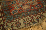 Tattered end of a collector's antique Bijar rug, showing worn pile and red, blue Herati motif.