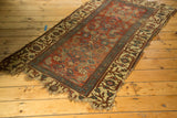 Tattered ends and pale saffron border with stylized floral motifs on the antique Bijar rug.