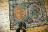 Antique Caucasian rug: bold geometric medallion, serrated border, rich navy, tangerine hues.