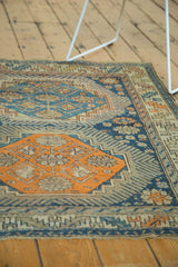 Close-up of antique Caucasian rug with tangerine hexagonal medallion and serrated leaf border.