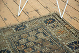 Antique Caucasian rug corner, highlighting tattered fringe and serrated border in teal, orange tones.