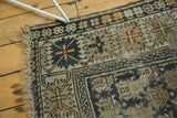 Antique Caucasian rug corner, dark blue floral cross-section, serrated border, worn fringe.