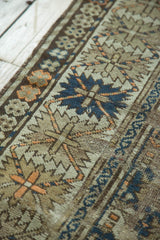 Antique Caucasian rug's dark teal floral cross-section, serrated border, and soft wear revealing foundation.