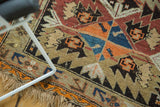 Antique Caucasian geometric rug detail: serrated motifs in tangerine orange, sky blue, and textured fringe.