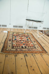 Dog-eared corner, tattered fringe, and geometric border of an antique Caucasian rug.
