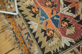 Tattered fringe and tangerine orange serrated motifs on an antique Caucasian rug.