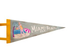 Vintage Miami Beach felt pennant with playful graphic of woman, palm tree, umbrella.