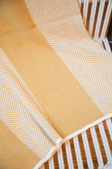 Mustard and white herringbone pattern detail on the soft textile blanket.
