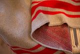 Folded knit throw with red and light gray stripes, revealing speckled red reverse.