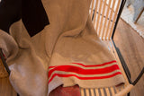 Textured knit Eco-Friendly blanket, showing black Swiss cross and bold red stripes.