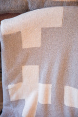 Folded gray and white Swiss cross blanket, highlighting visible knit texture.