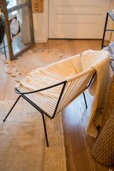 Ivory organic cotton Fisherman cable knit throw blanket draped softly.