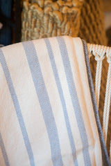 Close-up of blue and off-white woven blanket with herringbone stripes and stitched edge.