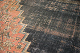 Antique Doroksh carpet detail: stepped border separates blush floral field from exposed dark foundation.
