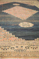 Antique Doroksh carpet's lily and vine border, blush spandrel, fringe, and deep navy patina.