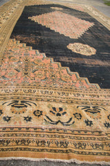 Antique Doroksh rug's main border with checkered lily motif, blush spandrel, and aged dark field.