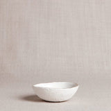 Organically shaped porcelain bowl with a textured exterior and delicate 22k gold rim.