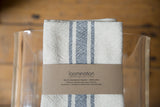 Folded gray and cream striped handwoven napkin set with a brown Loomination label.