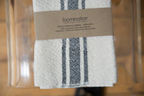 Loomination label over handwoven black and cream striped cotton napkin, revealing texture.