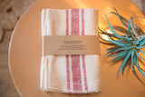 Handwoven Loomination cotton napkins, cream with prominent vertical wine red stripes.