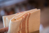 Handwoven sienna and cream striped cotton napkins folded, highlighting woven texture.