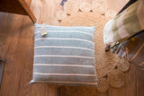 Hand-woven striped pillow featuring light green and cream interwoven texture, 20x20 inches.