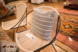 Hand-woven striped pillow with grey and off-white stripes on a modern rope chair.