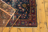 Delicate floral vinery and serrated leaves on indigo Yezd rug with worn pile.