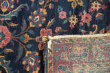Vintage Yezd rug corner showing indigo floral pile, woven foundation, fringe, and side wear.