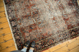 Worn vintage Lilihan rug edge, with faded brick red pile, navy border, and small hole.