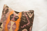 Textured flatweave with orange, purple, brown geometric patterns on vintage Kilim pillow.
