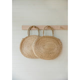 Two round seagrass bags with braided handles and natural woven texture.