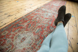 A long perspective of the antique Heriz runner highlighting its low-pile texture and ruby-red pattern.