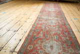 A long perspective view of the antique Heriz runner, highlighting its column of medallions and consistent wear.
