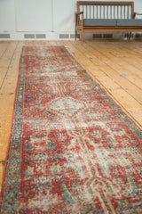Angled perspective of an antique Heriz runner showing the worn patina on its long ruby red field.