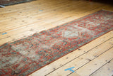 Angled view of an antique Heriz runner's length, showing mostly even wear and exposed foundation.