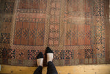Antique Turkmen rug with faded blush geometric garden panels and navy motifs.