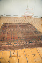 Worn end of antique Turkmen rug, showing geometric border in faded rose and blue tones.