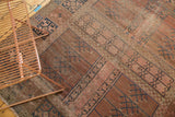 Close-up of antique Turkmen rug with primitive blue geometric panels, faded blush tones, and exposed foundation.