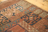 Antique Turkmen rug's primitive geometric pattern in faded blush, navy, teal, showing wear.