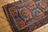 Fine vintage Hamadan rug corner, showcasing tattered fringe and brick red, blue geometric borders.