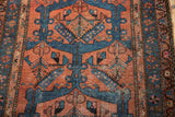 Brick red field with sky blue geometric motifs and germinating plants on vintage Hamadan rug.