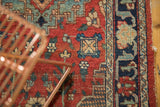 Vintage Tabriz rug's low pile cherry red field, germinating plants, and navy vine border.