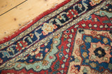 Vintage Tabriz runner with navy border, red floral field, intricate arabesques, and side tatter.